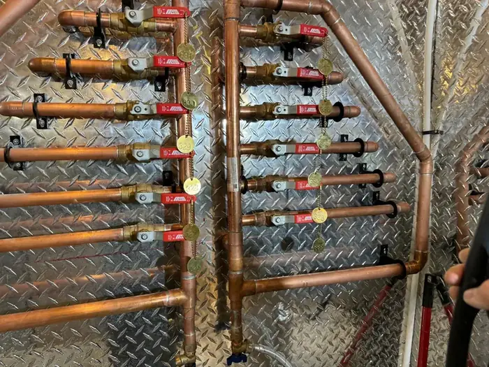 A copper manifold with every valve tagged and numbered.